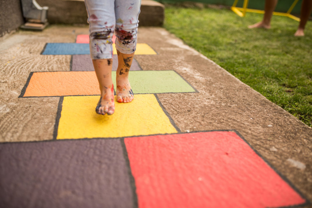 child playing hopscotch on painted pavement