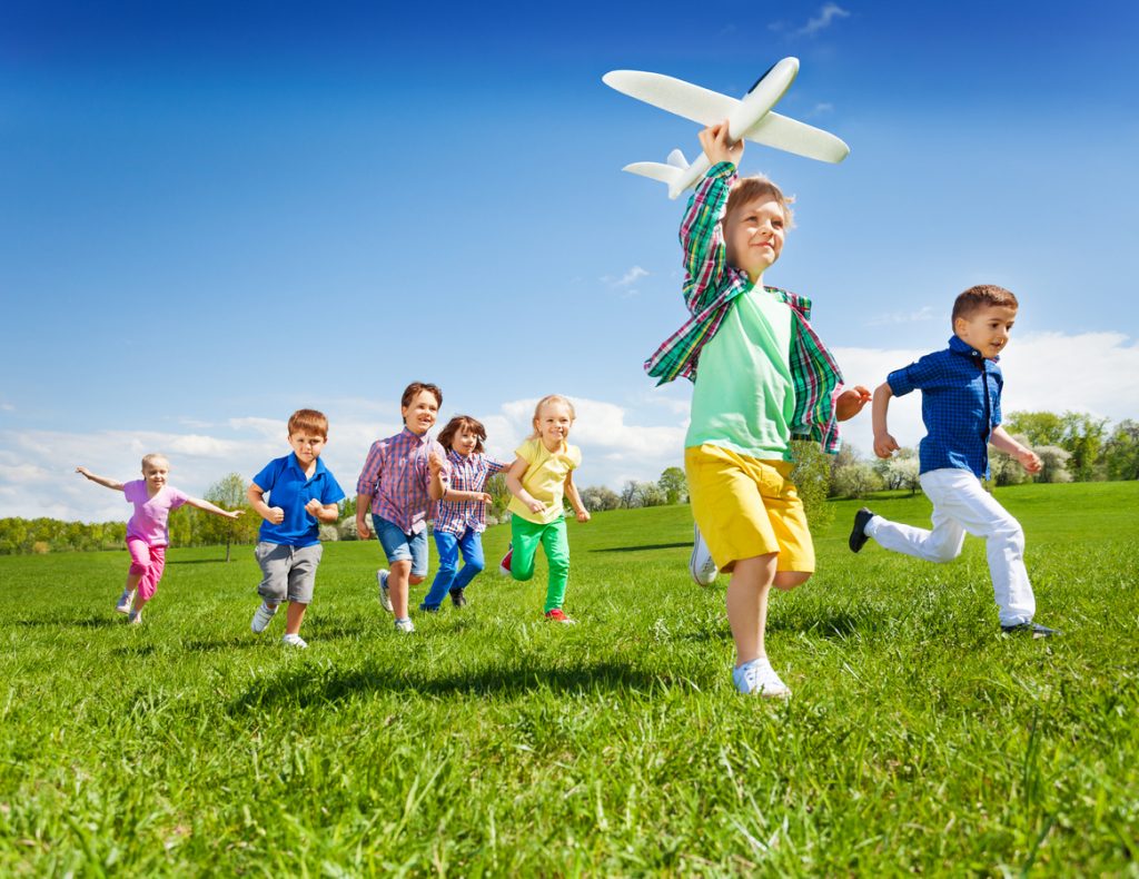 Active running kids with boy holding airplane toy