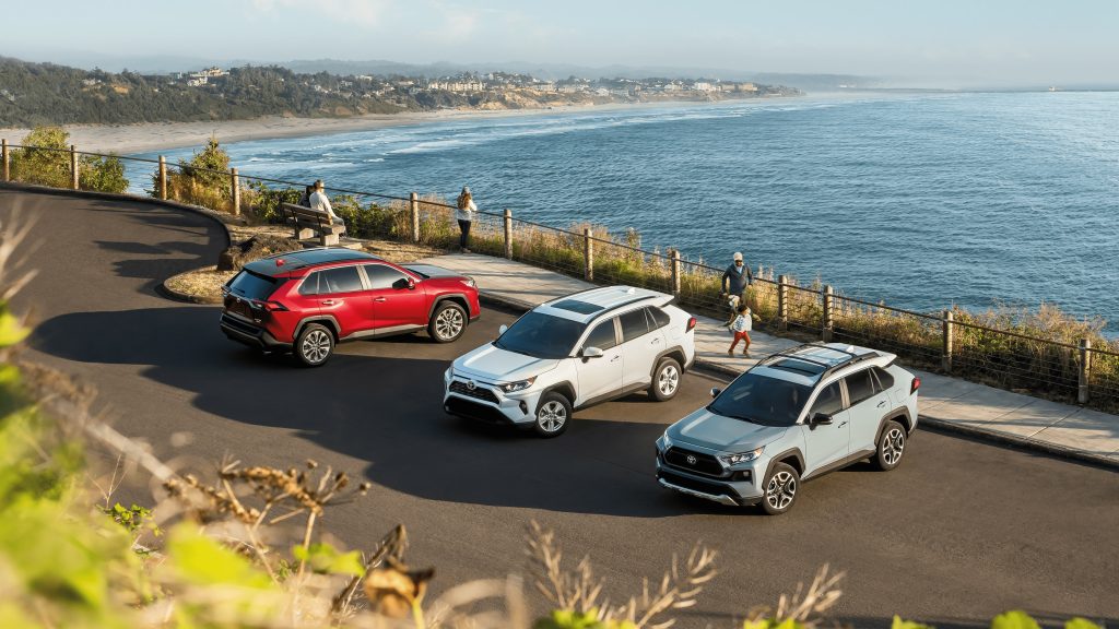 Three 2020 RAV4 models parked in a parking lot overlooking a beach
