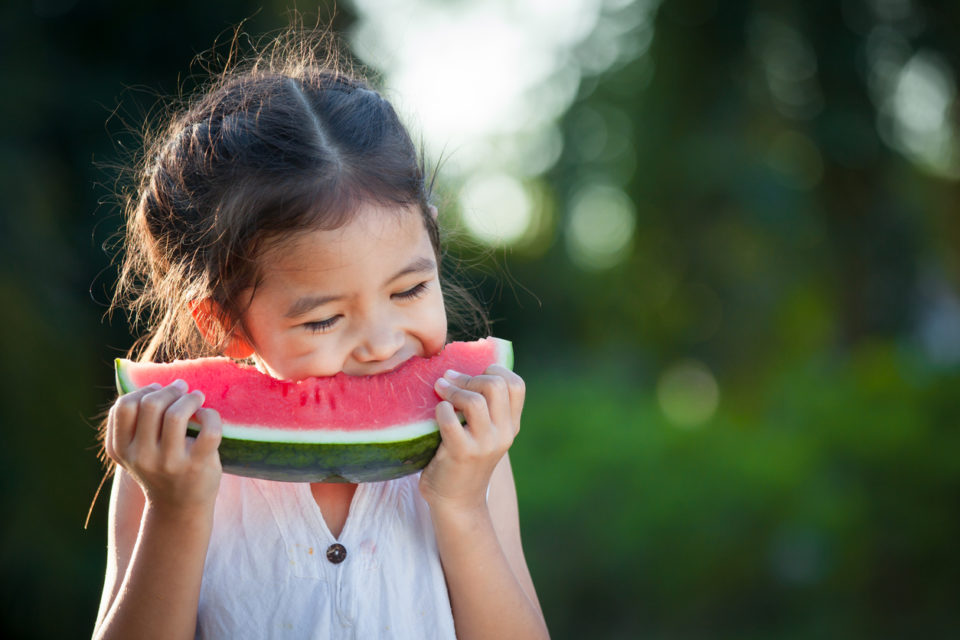 Little girl eating watermelon outside.