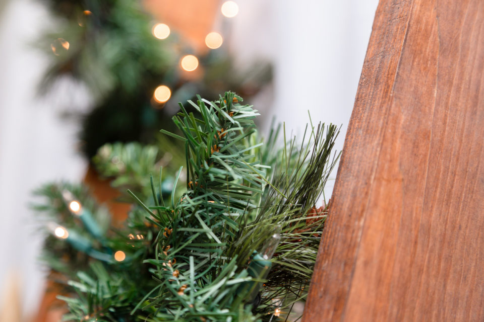 A wooden staircase is decorated with a garland of a Christmas tree and lights. Close-up
