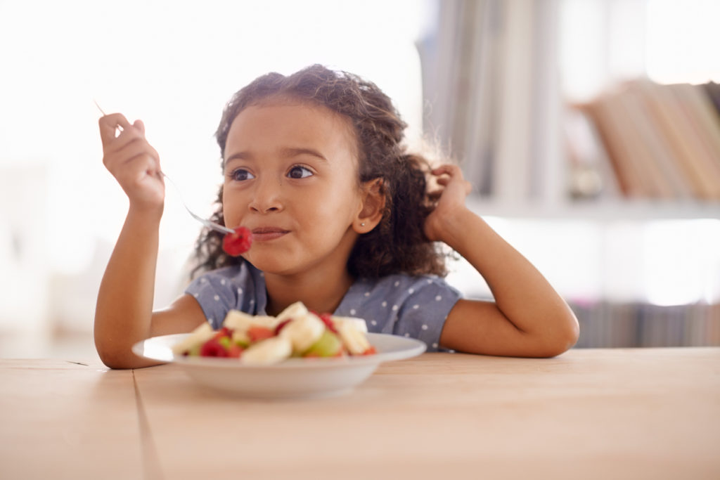 little girl eating fruit salad