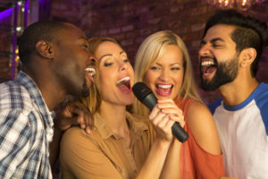 Group of friends singing into microphone.